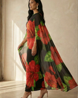 Woman wearing a floral dress with red and green flowers on a neutral background
