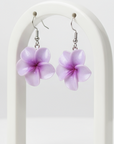 Purple flower-shaped earrings on a white arch background