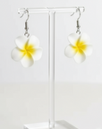 Flower-shaped earrings on a white fabric background