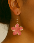 Close-up of a pink flower earring worn by a person.