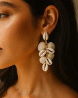 Close-up of a woman wearing shell earrings with a neutral background