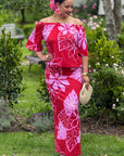 Woman in a red and pink floral dress standing in a garden.