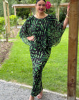 Woman in a green and black patterned outfit standing outdoors.