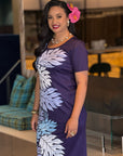 Woman wearing a purple dress with leaf patterns indoors