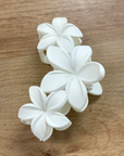 White floral hair clip on a wooden surface