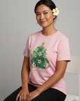 Woman wearing a pink t-shirt with a floral design, sitting on a white chair against a gray background.