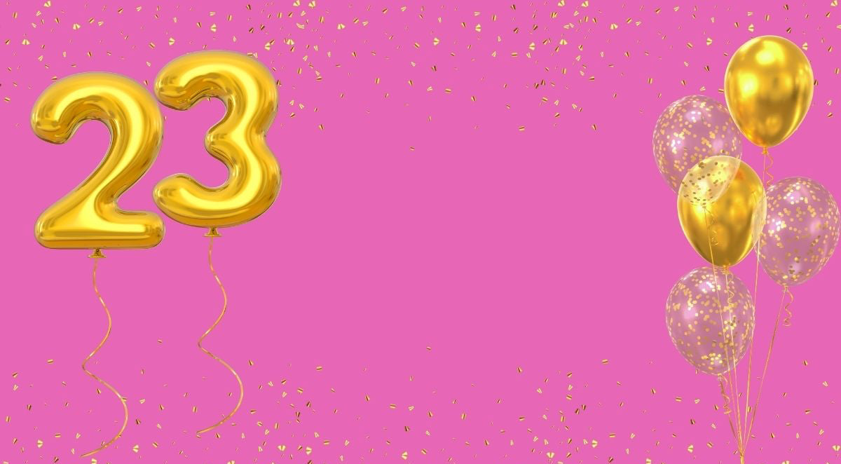 Gold number '23' balloons and confetti on a pink background