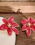 Pink flower-shaped earrings on a wooden surface