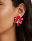 Pair of red flower-shaped earrings on a dark surface