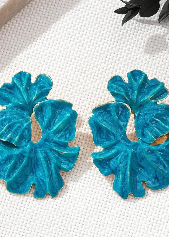 Pair of blue earrings on a white fabric background