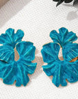 Pair of blue earrings on a white fabric background