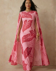 Woman wearing a pink dress with leaf pattern against a beige background