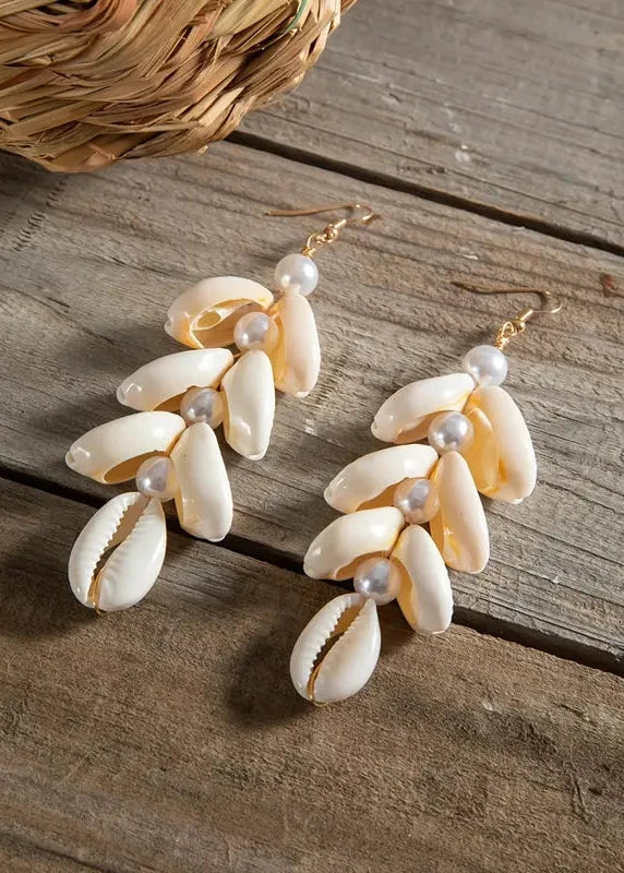 Shell and pearl earrings on a wooden surface