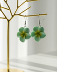 Green flower-shaped earrings on a white background