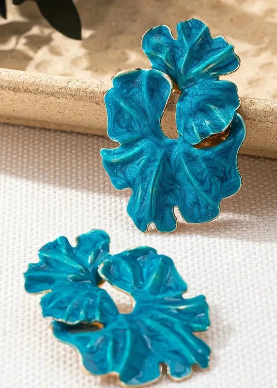Pair of blue floral earrings on a beige surface