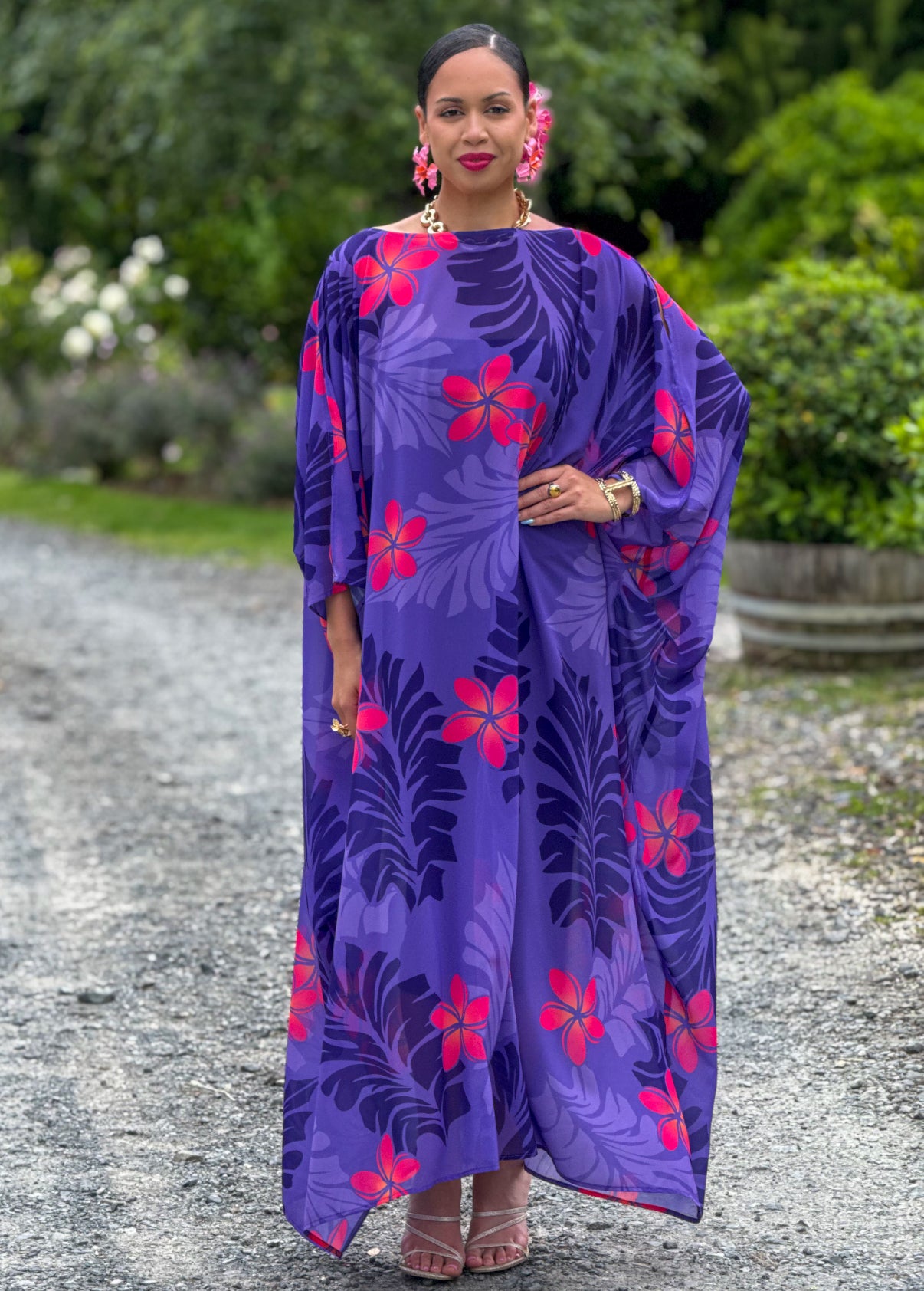 Woman wearing a purple dress with pink floral patterns standing outdoors.
