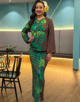 Woman in a brown and green leaf-patterned outfit standing in an indoor setting.