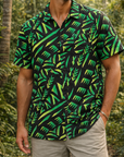 Man wearing a green and black patterned shirt in a tropical setting