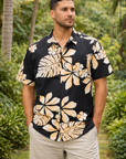 Man wearing a black and beige floral shirt in a tropical setting