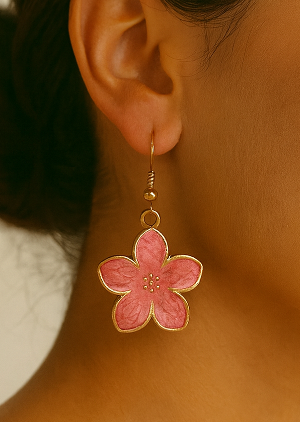 Close-up of a pink flower earring worn by a person.
