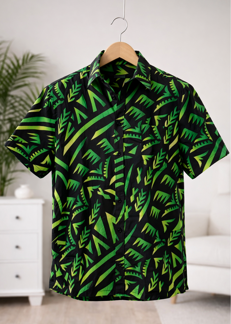 Green and black patterned shirt on a hanger against a white wall.