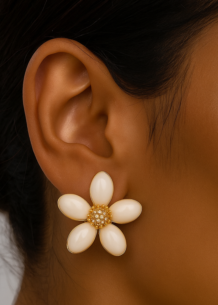 Close-up of an ear wearing a white flower-shaped earring with gold accents.