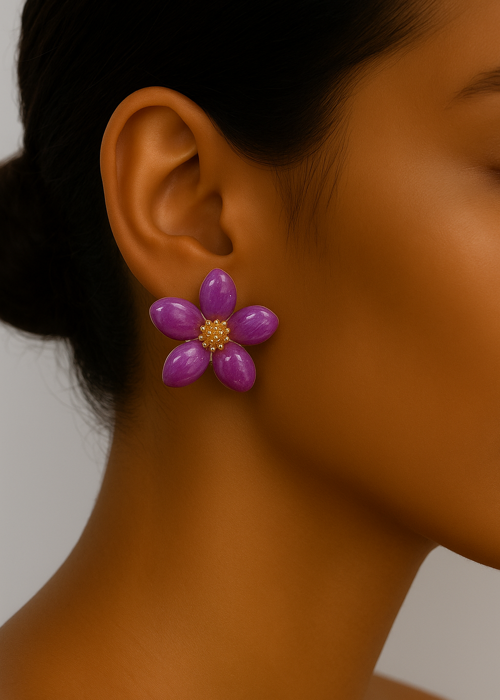 Close-up of a person wearing a purple flower-shaped earring against a neutral background