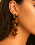 Close-up of a person wearing tortoiseshell leaf-shaped earrings.