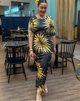 Woman in a black and yellow patterned dress standing in a modern indoor setting.