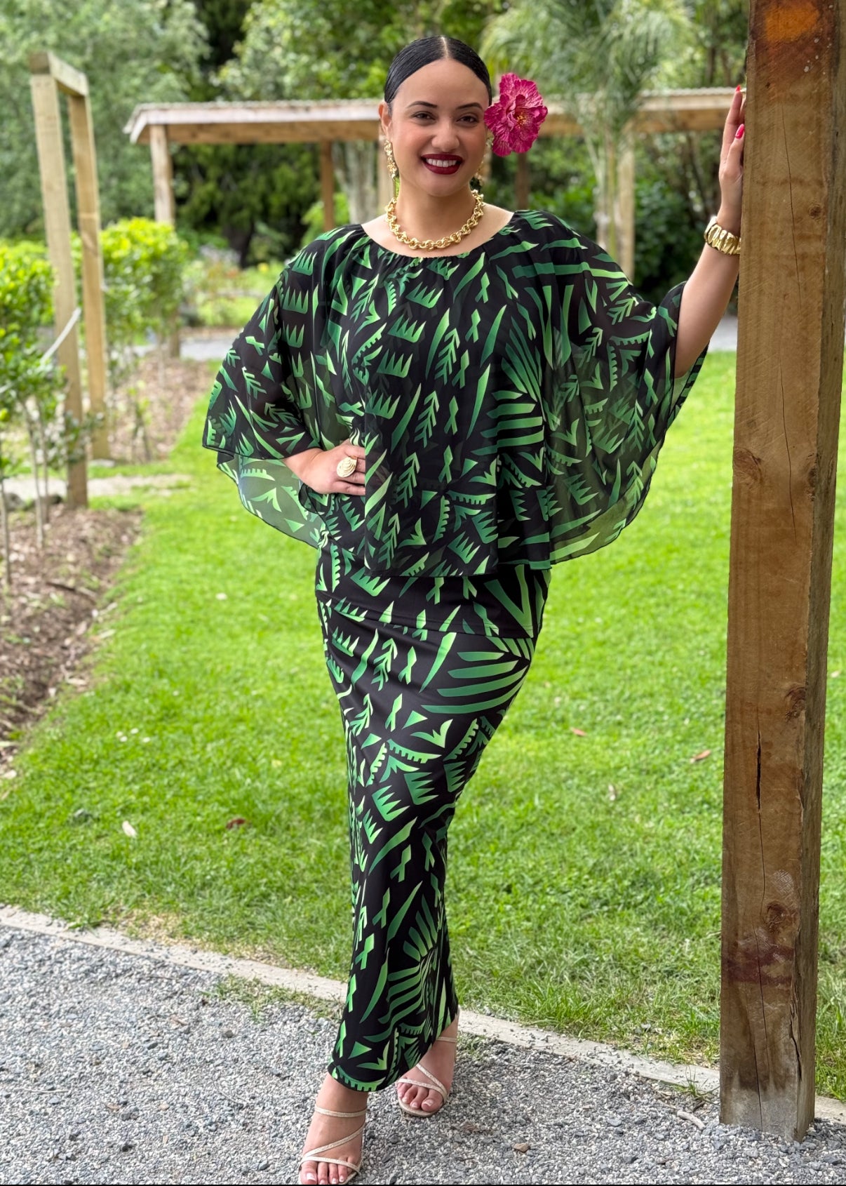 Woman in a green and black patterned outfit standing outdoors.