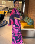 Woman in a colorful dress standing in a modern indoor setting with decorative lighting and furniture.