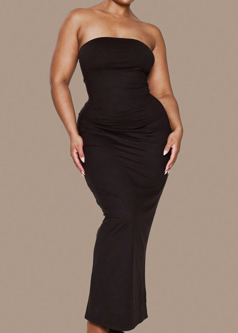 Woman wearing a black strapless dress against a beige background