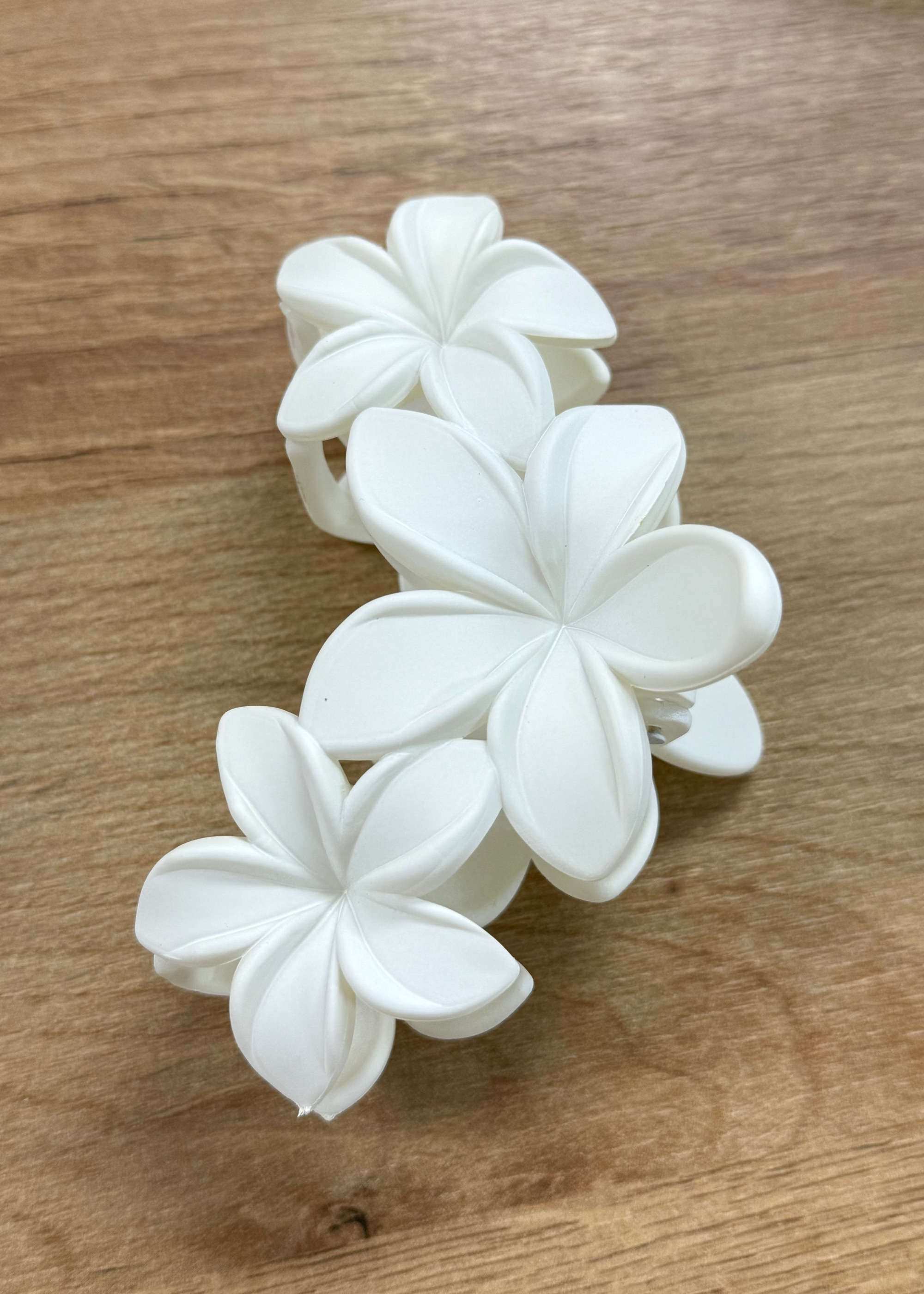 White floral hair clip on a wooden surface