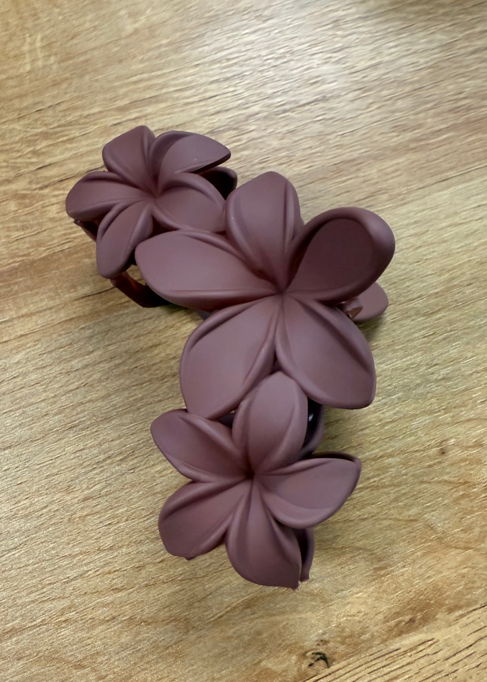 Purple floral hair clip on a wooden surface