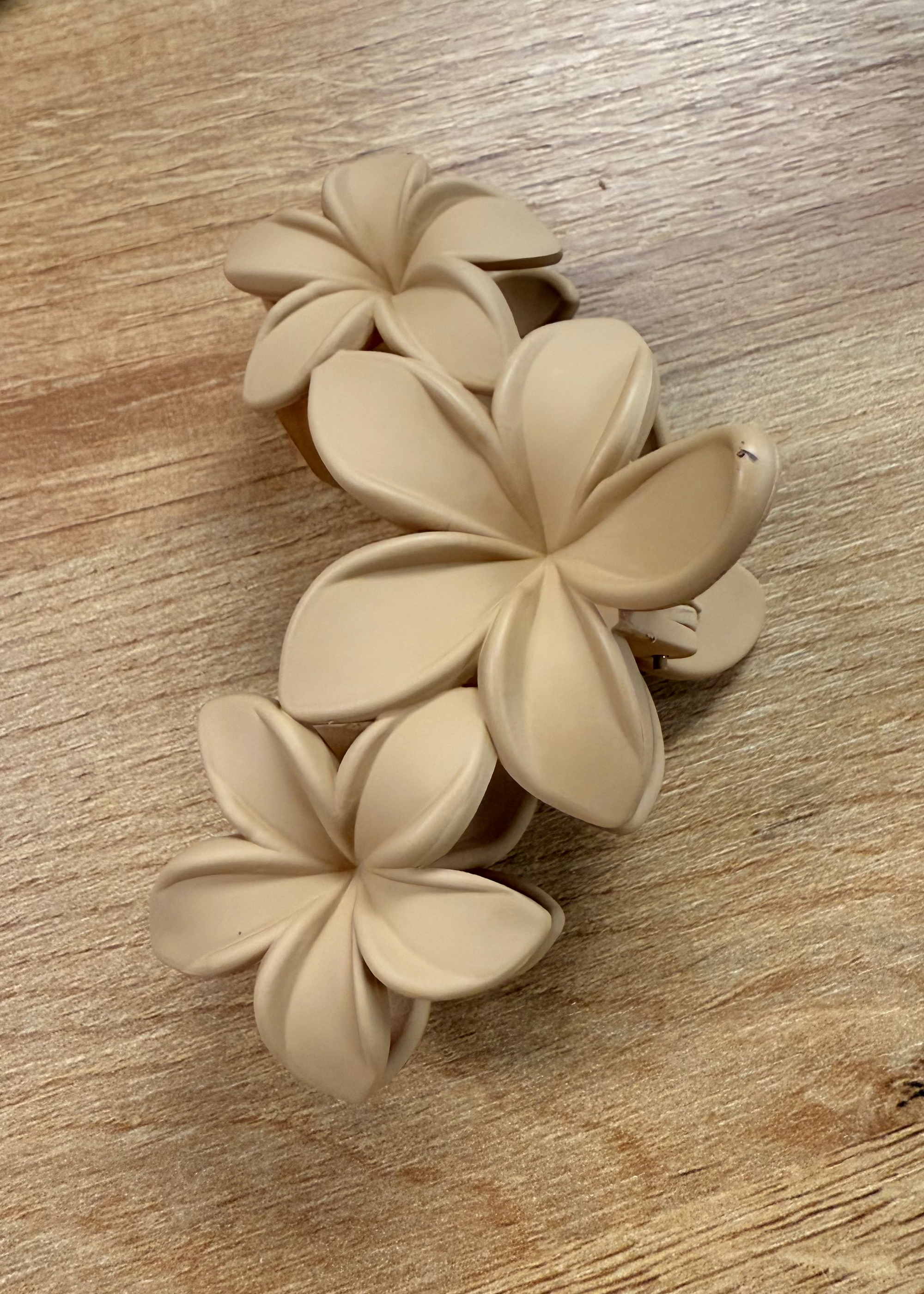 Beige floral hair clip on a wooden surface