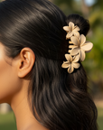 Woman with dark hair styled in an updo with a floral hair accessory, outdoors.