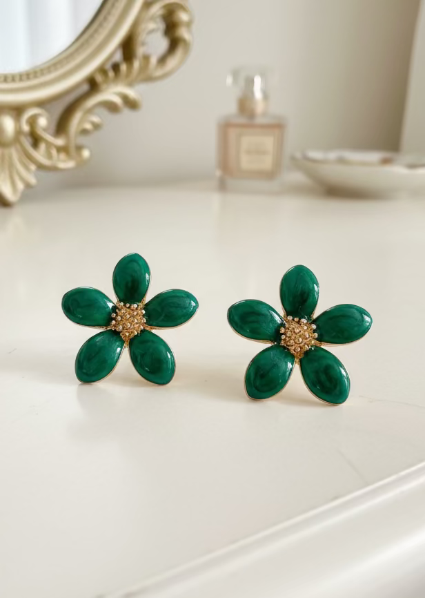 Green flower-shaped earrings on a wooden surface