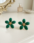 Green flower-shaped earrings on a wooden surface