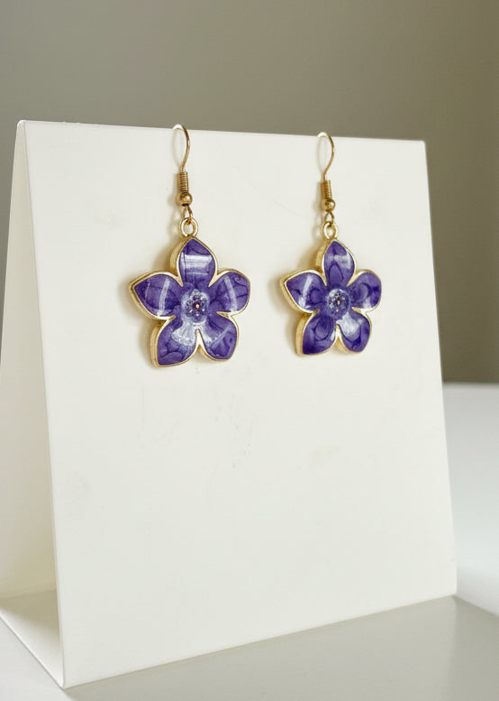 Purple flower-shaped earrings on a white background