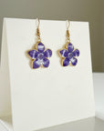 Purple flower-shaped earrings on a white background