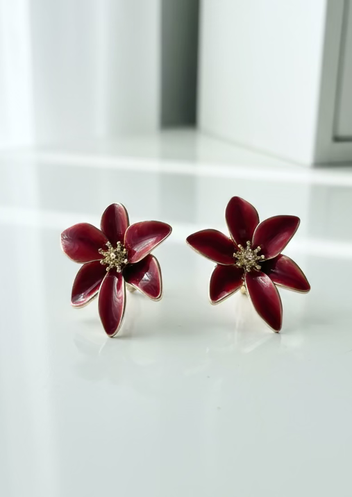 Red flower-shaped earrings on a wooden surface