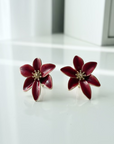 Red flower-shaped earrings on a wooden surface