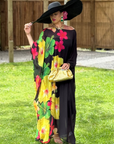 Woman in a colorful floral dress and black hat standing on grass