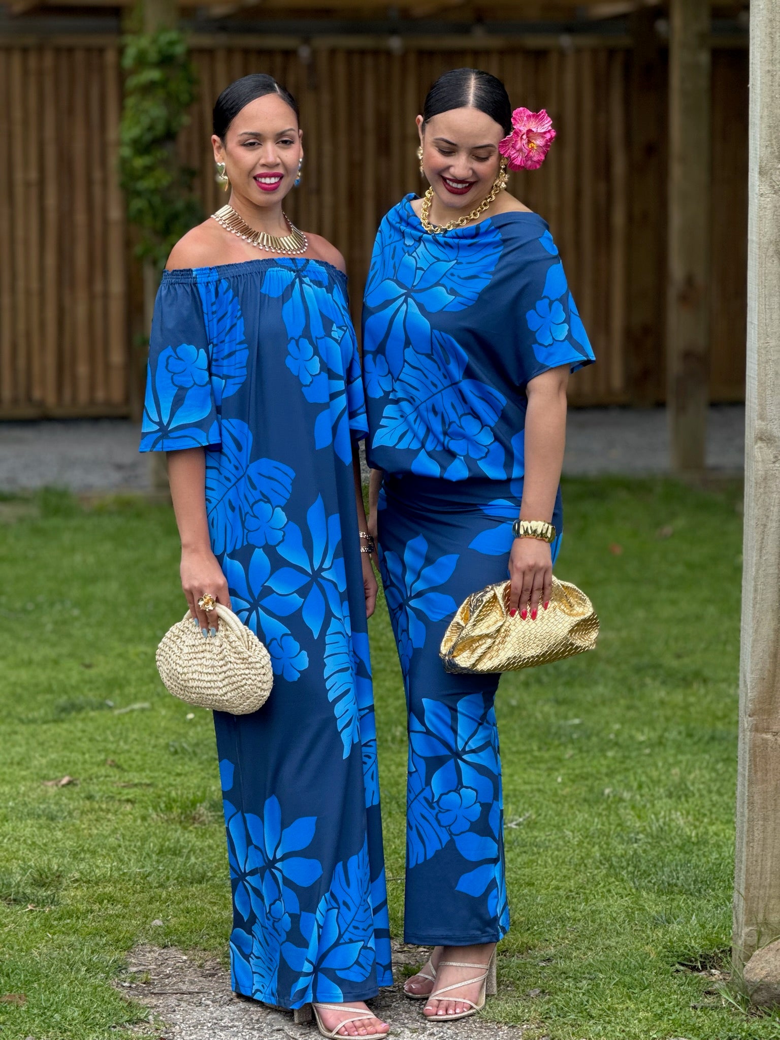 Two women in matching blue floral outfits standing outdoors.
