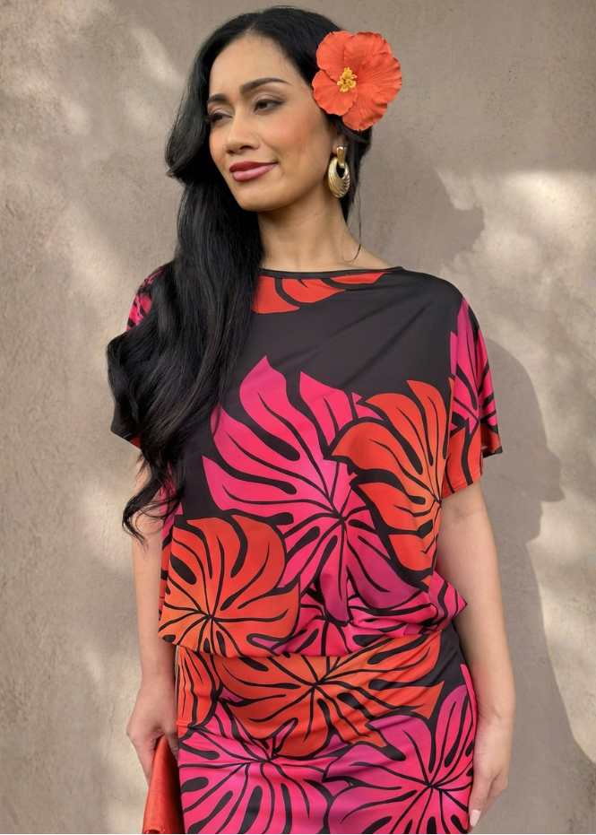 Woman wearing a black dress with red and pink floral patterns against a neutral background
