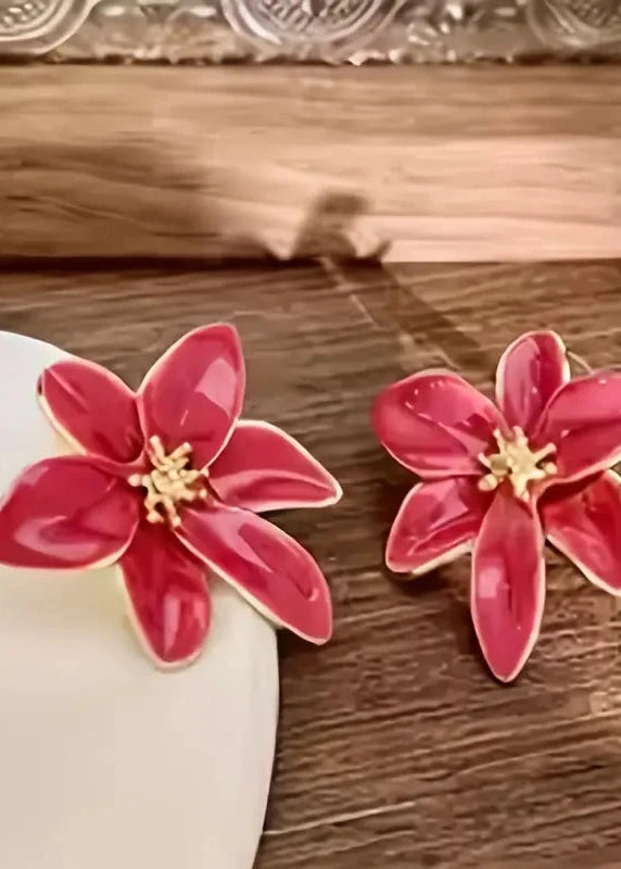 Pink flower-shaped earrings on a wooden surface
