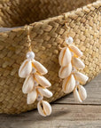 Shell and pearl earrings on a wooden surface with a woven basket in the background