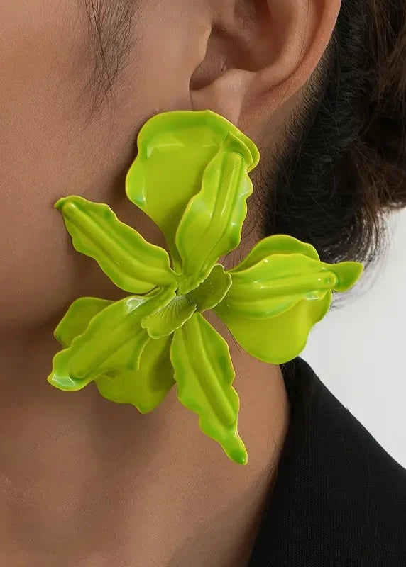 Close-up of a person wearing a bright green floral earring against a neutral background